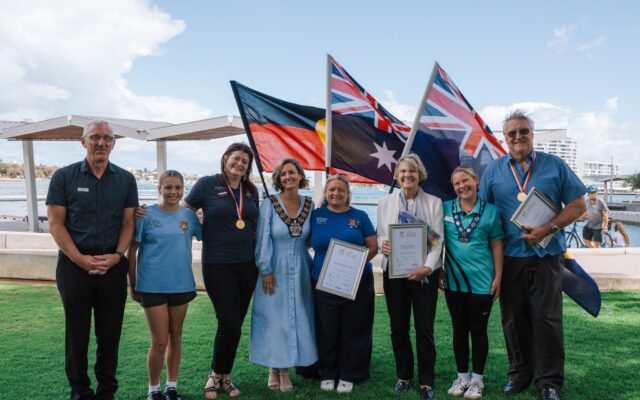 people smiling some holding certificates with Australian and Aboriginal flags behind